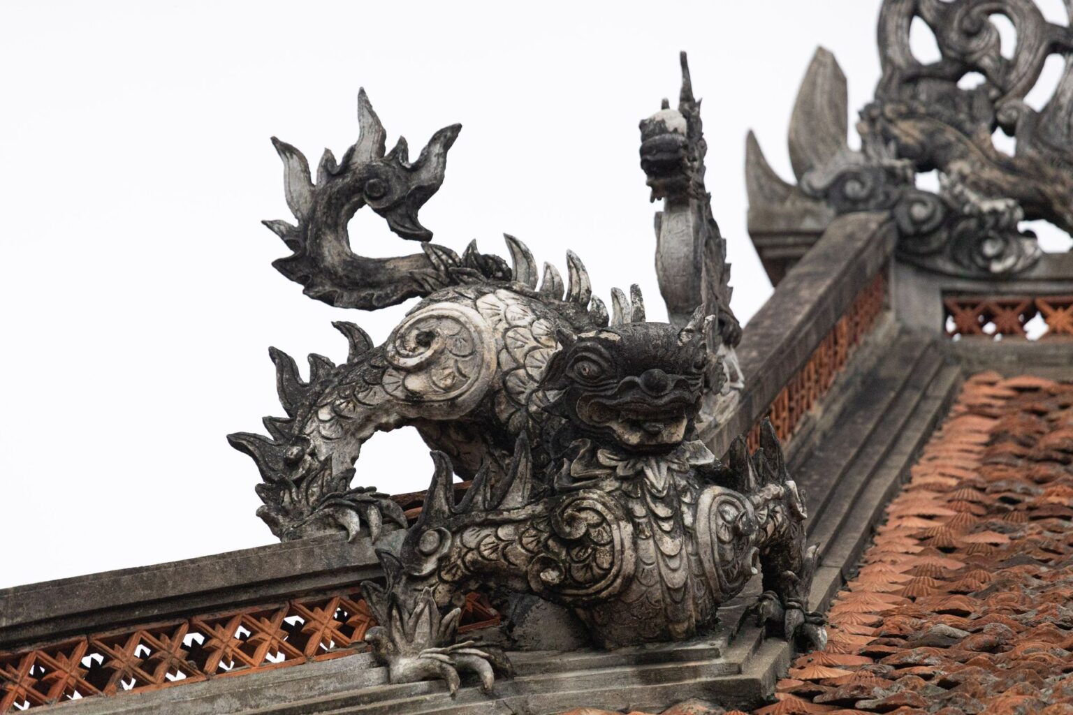 Qui sont les créatures fabuleuses des légendes ? Sculpture de dragon complexe au sommet d'un toit traditionnel à Hà Nội, Việt Nam.